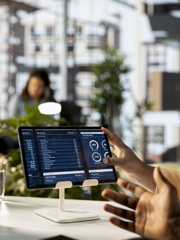 African American company employees handling financial planning in a corporate office, emphasizing teamwork to guarantee enterprise growth. Coworkers study online reports. Close up.
