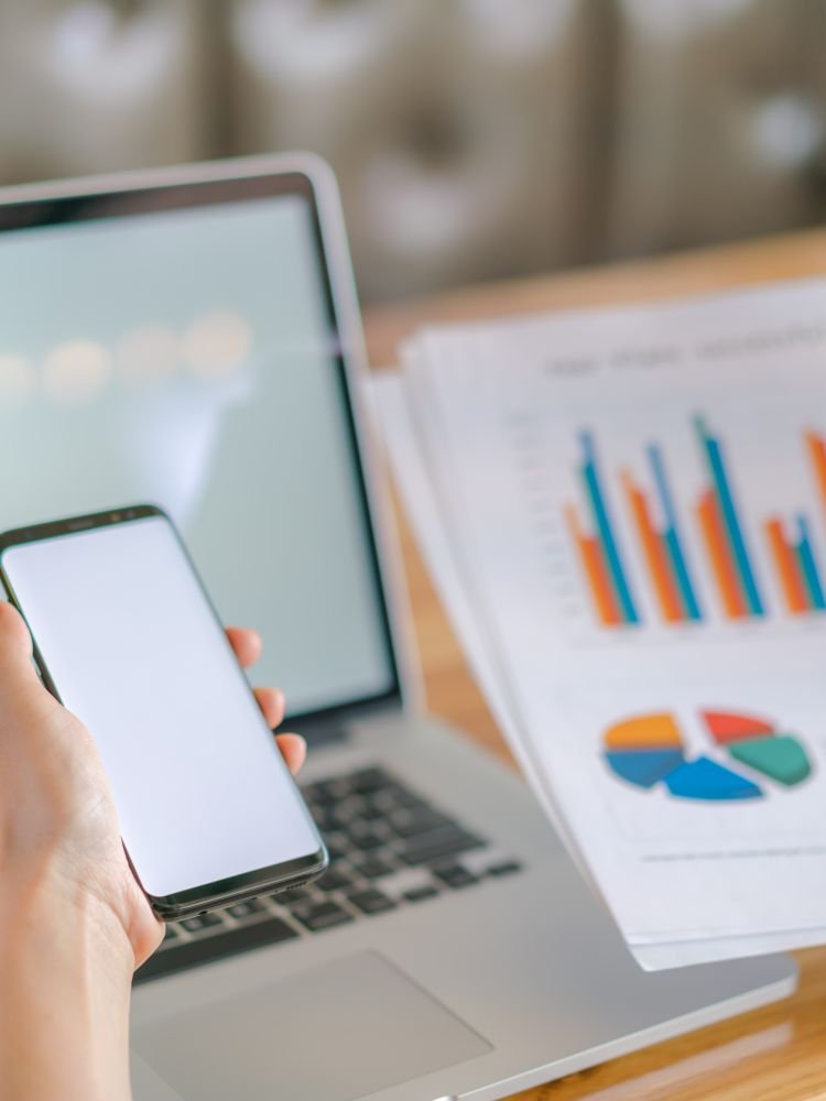 Business woman hand with Financial charts and mobile phone over laptop on the table